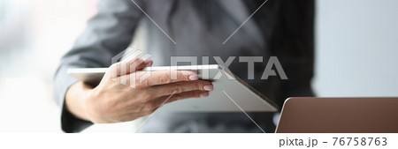 Business woman holding digital tablet and laptop in hands in office closeup Business woman holding digital tablet and laptop in hands in office closeup 76758763