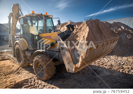 tractor with sand in the bucket on a clear day 76759452