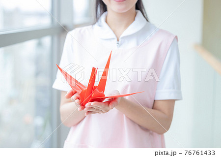 医療　折り鶴を持つ看護師の手元 76761433