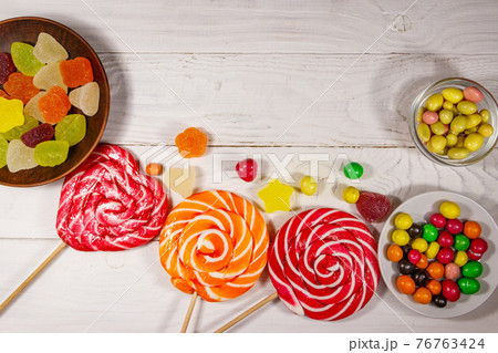 Colorful chocolate candies, lollipops and jelly sweets on white wooden table Colorful chocolate candies, lollipops and jelly sweets on white wooden table 76763424