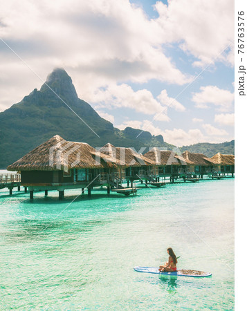 Tahiti Bora Bora beach vacation luxury hotel resort in French Polynesia. Woman paddleboarding doing watersport leisure activity on SUP. Mount Otemanu landscape summer holiday Tahiti Bora Bora beach vacation luxury hotel resort in French Polynesia. Woman paddleboarding doing watersport leisure activity on SUP. Mount Otemanu landscape summer holiday 76763576