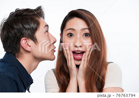 耳打ちする男性に驚く女性 76763794