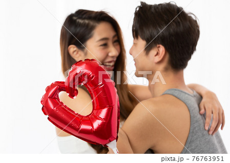 ハート越しに笑い合うカップル 76763951