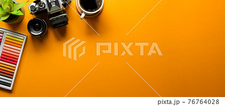 Yellow flat lay workspace with oil pastels, camera, coffee mug and copy space, top view 76764028