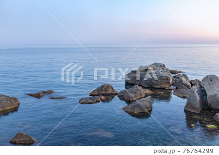 Twilght over the wild rocky beach coastline and the sea. Sea and rocks at night wide angle view. 76764299