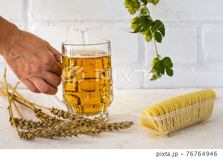 Glass of beer and potato chips on white background. 76764946