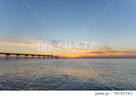 Early morning a few minutes before sunrise. Dawn on the sea with pontoon. Blue sky is painted in shades of orange. 76765762