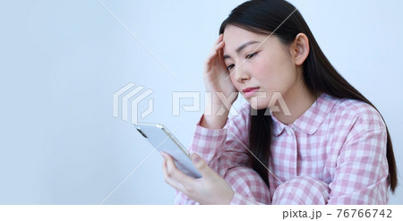 パジャマ姿でスマートフォンを操作する女性イメージ 76766742