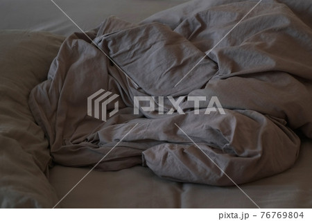 Flattened bed with chocolate-colored cotton linens, closeup view. 76769804