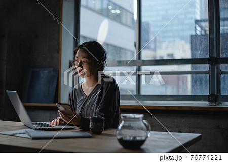 暗い部屋でパソコンを見つめる女性の写真素材