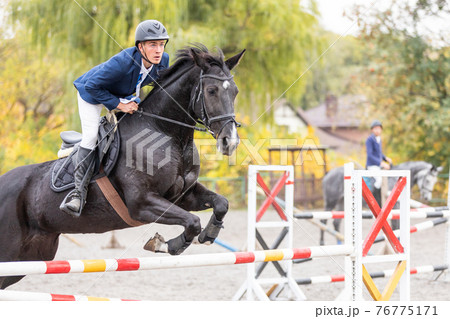 Young man jumps a horse on show jumping event 76775171