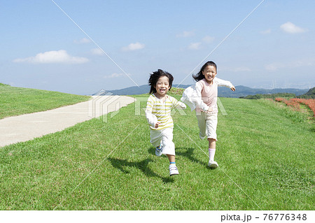 芝生を走る女の子と男の子 76776348