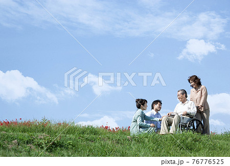 車椅子に座るシニア男性と笑顔の家族 76776525