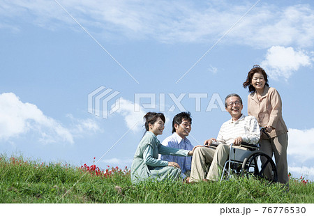 車椅子に座るシニア男性と笑顔の家族 76776530