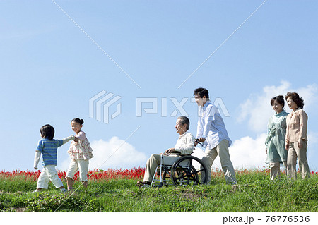 車椅子に座るシニア男性と笑顔の家族 76776536