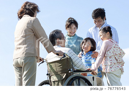 車椅子に座るシニア男性と笑顔の家族 76776543