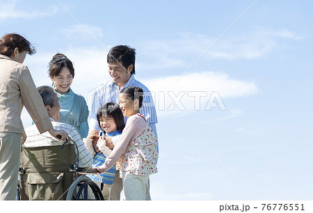 車椅子に座るシニア男性と笑顔の家族 76776551