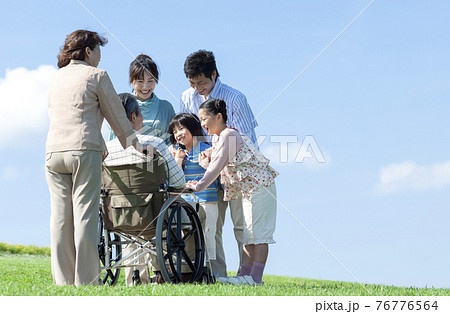 車椅子に座るシニア男性と笑顔の家族 76776564