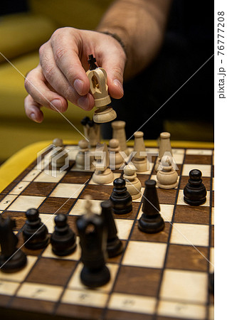 Man taking next step on chess game. Human hand moving wooden white chess king 76777208