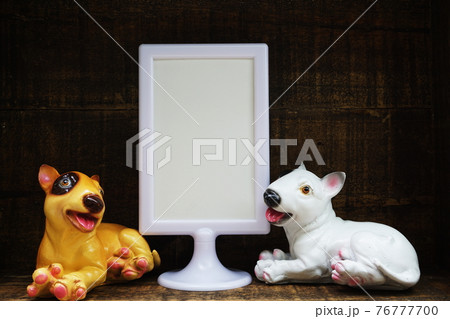Blank Display frame stand with Dog Stucco doll decoration on wooden background 76777700