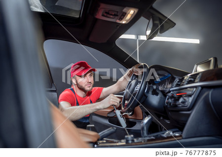 Man in overalls doing car maintenance 76777875