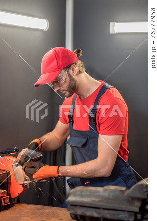 Attentive man machining detail on grinding machine 76777958