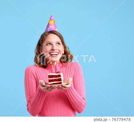 Delighted woman with cupcake making birthday wish Delighted woman with cupcake making birthday wish 76779478