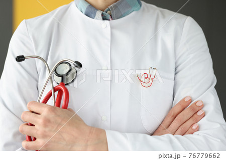 Doctor with brooch on uniform holding stethoscope closeup 76779662