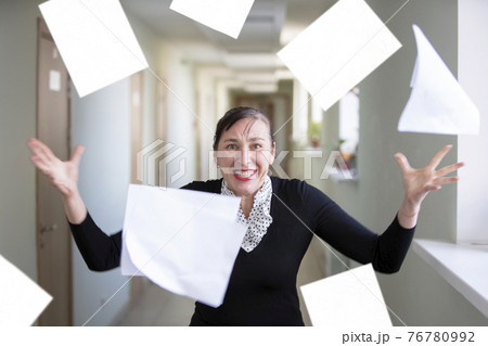 A woman in the office scatters papers. Nervous employee. 76780992