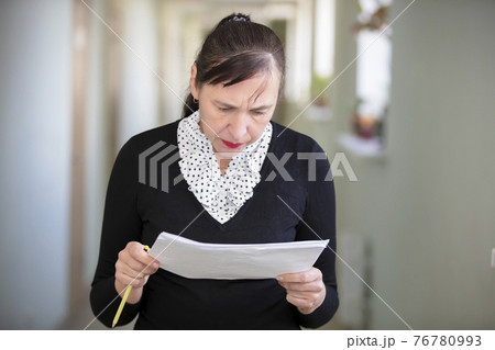 Woman at work. Female employee in the office corridor with paper. 76780993