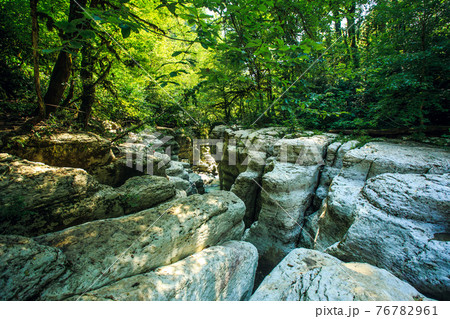 white rocks in Sochi. Waterfall in a crevice between the rocks behind the trees 76782961