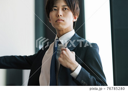 スーツの上着を羽織るビジネスパーソン 76785280