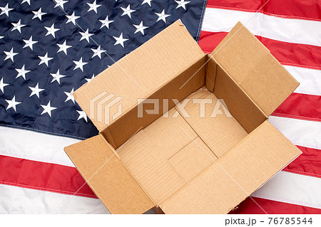 USA flag with open shipping box. Delivery from the USA. Empty postal box on American flag USA flag with open shipping box. Delivery from the USA. Empty postal box on American flag 76785544