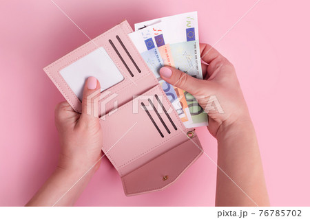 Hands holding wallet. Pink leather wallet with euro money in female hands. Closeup on a woman's hands taking European bank notes out of purse and counting. Concept of money, finances, shopping, cash. 76785702