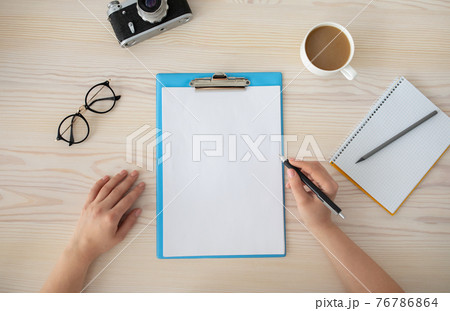Female hands writing plan for trip in empty notepad at the wooden desk, top view, copy space for text. 76786864