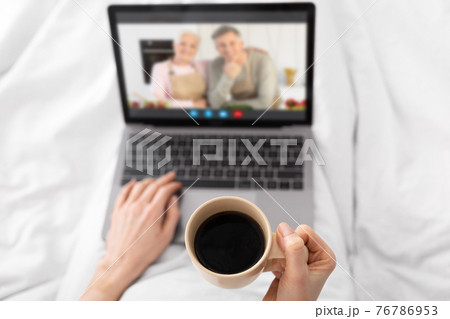 Unrecognizable Female Drinking Coffee In Bed And Making Video Call To Parents 76786953