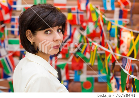 Brunette woman looking over her shoulder back against a background of different flags Brunette woman looking over her shoulder back against a background of different flags 76788441
