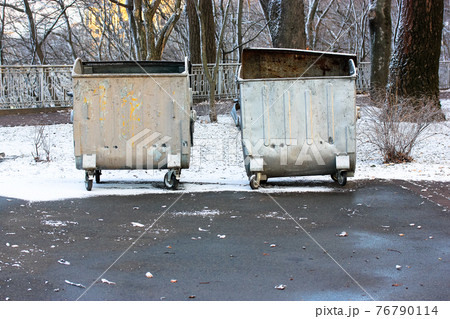 Metal garbage cans, recycling bins, trash containers on wheels in a winter park. Metal garbage cans, recycling bins, trash containers on wheels in a winter park. 76790114