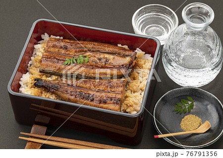 黒バックに置いた鰻重と日本酒 76791356