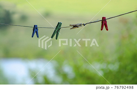 Colorful clothespin clothespins on the rope. Colourful cloth clips in a blue rope waiting for the next batch of clothes to come after laundry. 76792498