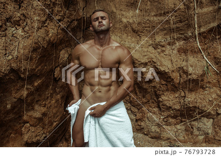 Strong face muscle male model on the nature background with sand stones and water on the beach on the sunset 76793728