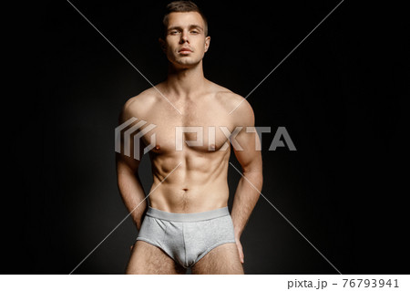 Strong stripped muscle male model in gray underwear on black isolated font background 76793941