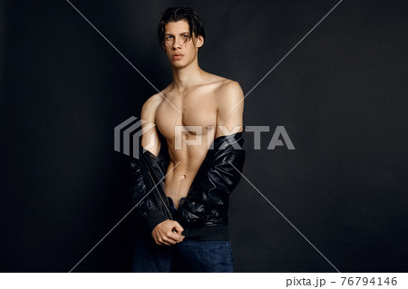Male model in denim blue jeans and black leather jacket on black background 76794146
