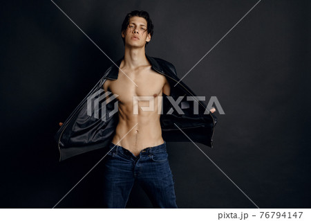Male model in denim blue jeans and black leather jacket on black background Male model in denim blue jeans and black leather jacket on black background 76794147