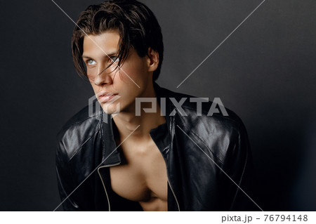 Male model in denim blue jeans and black leather jacket on black background 76794148