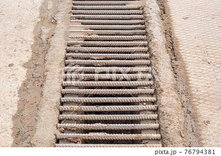 drainage grate made of iron rods fittings dirty in a swamp made of clay, infrastructure system of industrial wastewater close up, nobody. drainage grate made of iron rods fittings dirty in a swamp made of clay, infrastructure system of industrial wastewater close up, nobody. 76794381