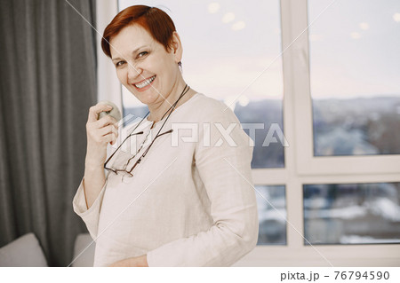 Mature smiling woman with glasses posing at home Mature smiling woman with glasses posing at home 76794590