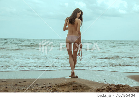 Stunning beautiful dark hair girl stripped in swimsuit on the sunset at he beach 76795404