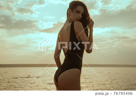 Stunning beautiful dark hair girl stripped in swimsuit on the sunset at he beach 76795406