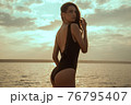 Stunning beautiful dark hair girl stripped in swimsuit on the sunset at he beach 76795407